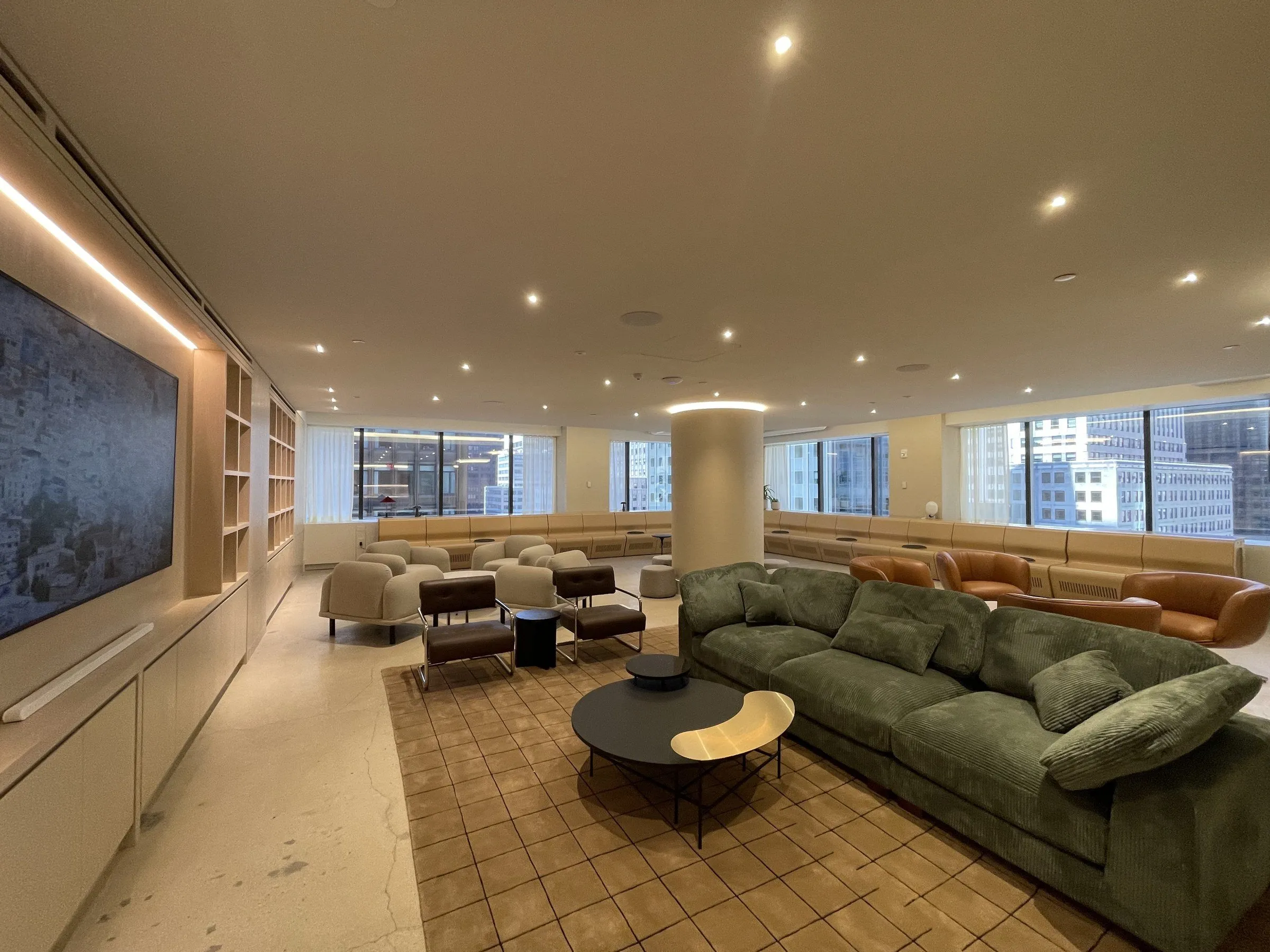 A Manhattan amenity lounge with polished floors, walnut millwork, and green velvet seating